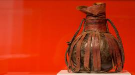 An ancient wooden jug wrapped in a leather casing 